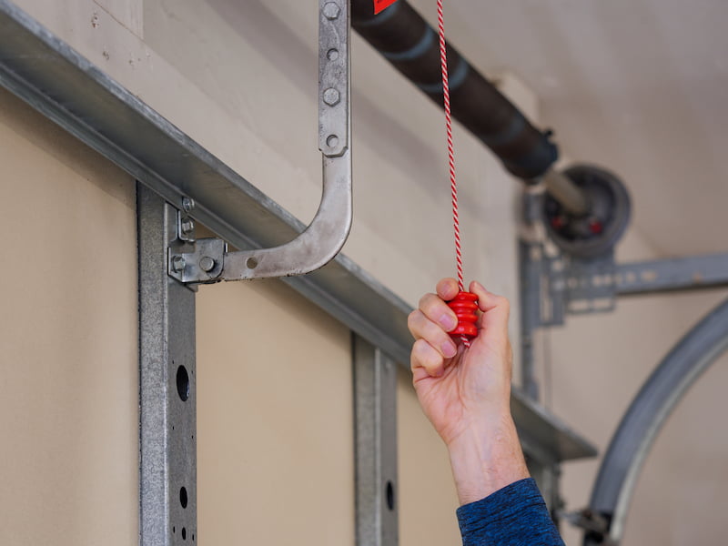 Hand puling on a garage door emergency release cord