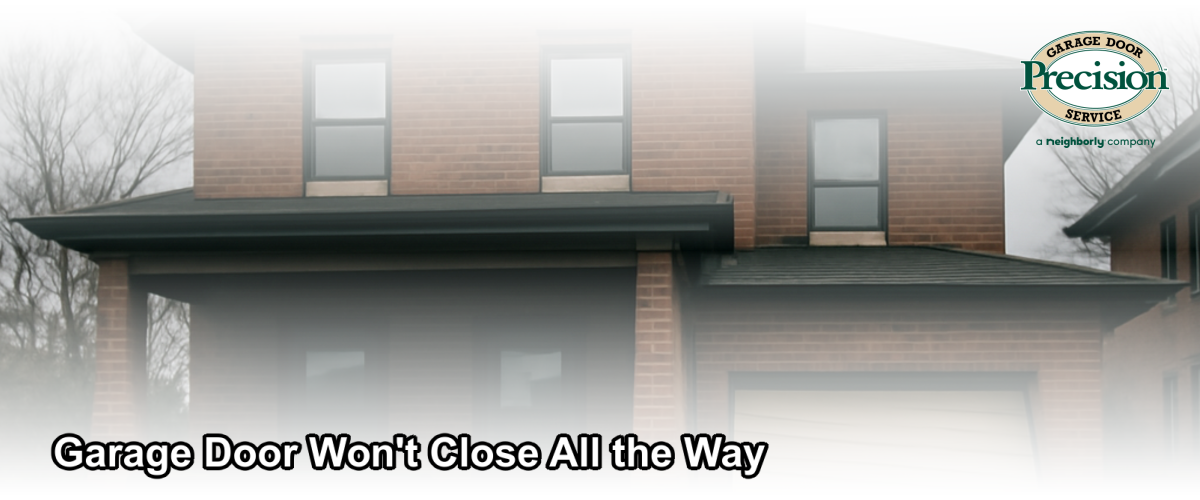 A residential garage door partially open and stuck, not closing all the way, on a Chicago home in winter